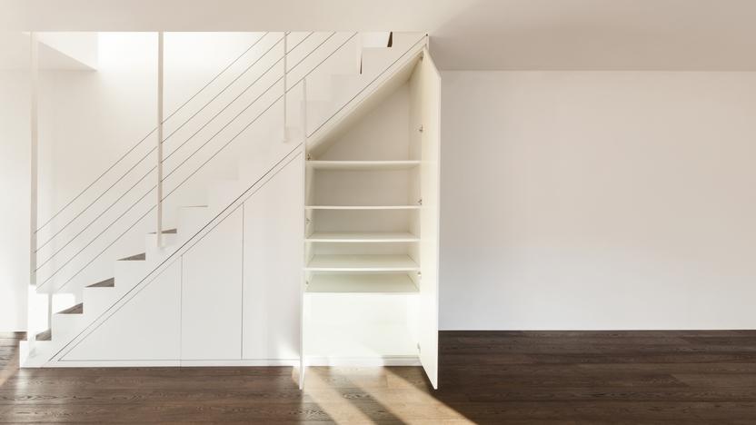 Nischenlösung für Einbauschrank unter Treppe Geräumiger Einbauschrank unter weißer Treppe mit Schubläden und Türen und offener Regalgestaltung an dunklem Parkett